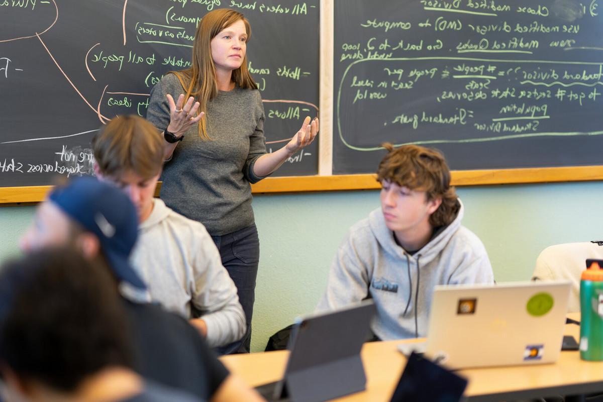 Beth Malmskog teaching to a class in front of a blackboard